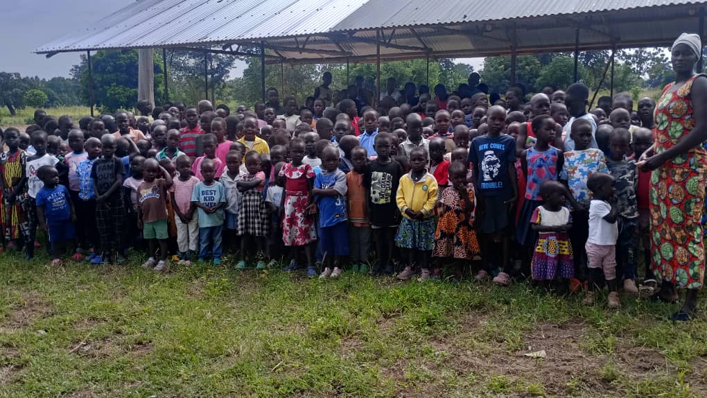 A large group of children gathered together under a community shelter