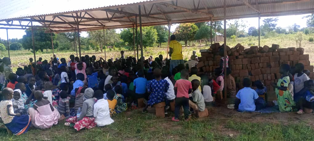 Children seated under a shelter